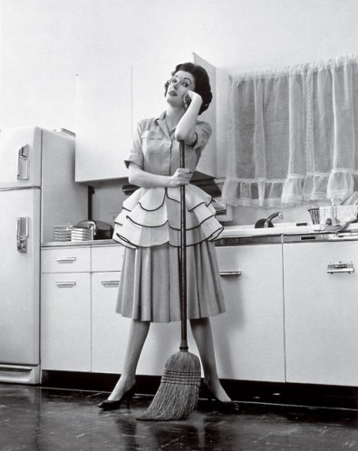 1950s Woman Housewife Standing In Kitchen Leaning On Broom